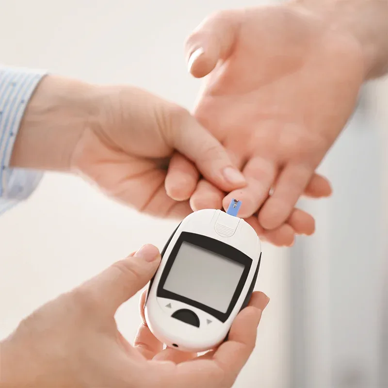 Healthcare professional taking a finger-prick capillary blood sample with a glucose meter for a blood sugar test at home in Dubai