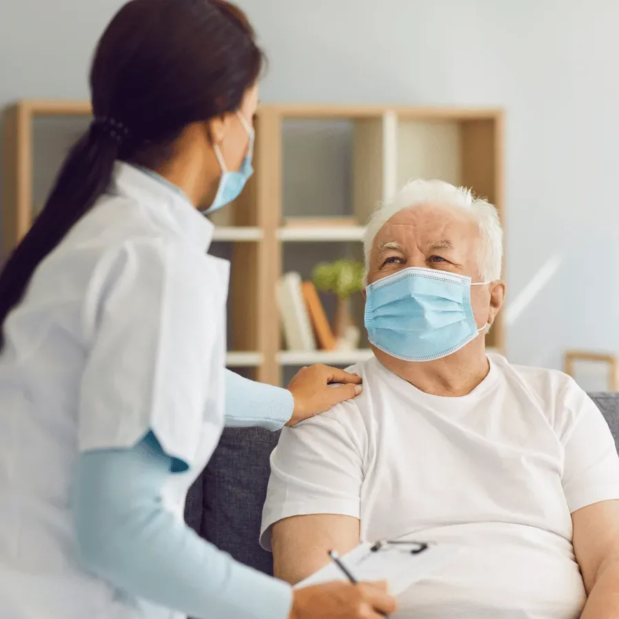 A DHA-certified Vesta Care home healthcare professional in a mask checking on an elderly masked patient at home before a COVID-19 PCR swab in Dubai