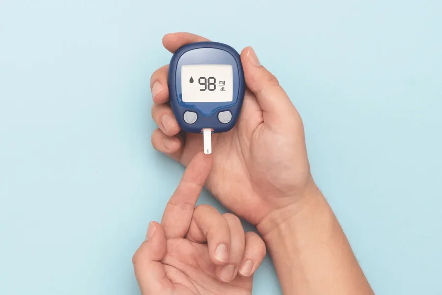 Fingertip blood glucose meter displaying a reading