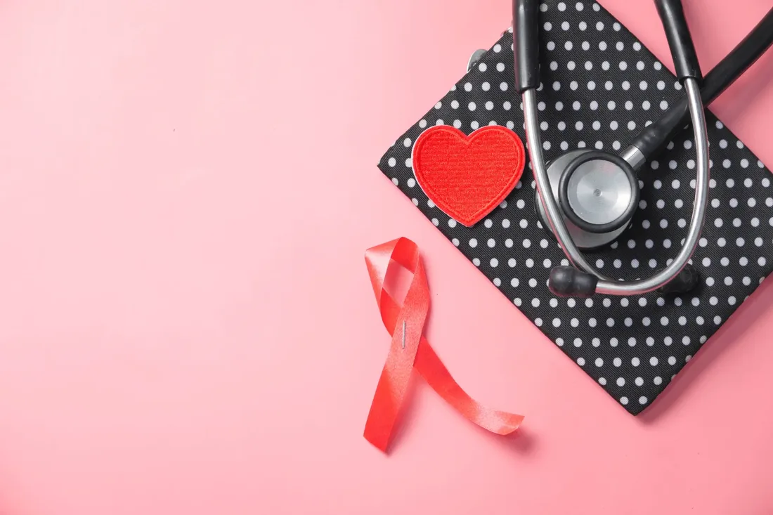 A red HIV awareness ribbon beside a stethoscope, representing confidential HIV testing at home in Dubai