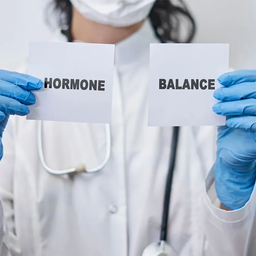 A clinician in Dubai holding cards showing the words hormone and balance during a hormone test consultation