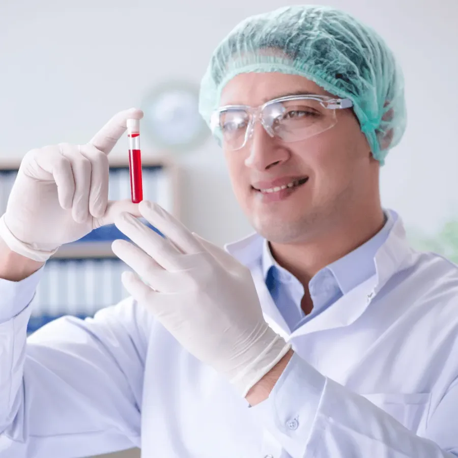 DHA-licensed laboratory technician in a hairnet and gloves holding a labelled blood sample tube for a testosterone test at home in Dubai