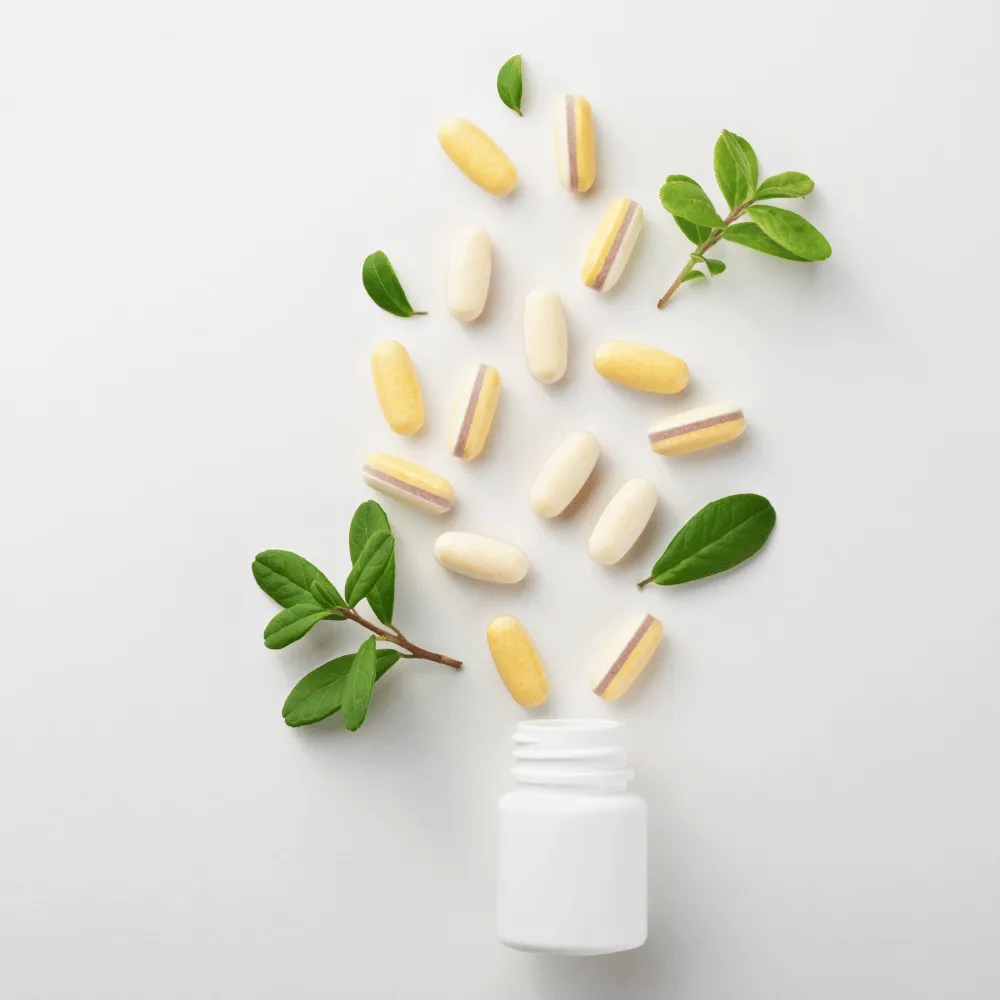 Vitamin tablets spilling from a white supplement bottle beside fresh green leaves, for a vitamin profile blood test at home in Dubai