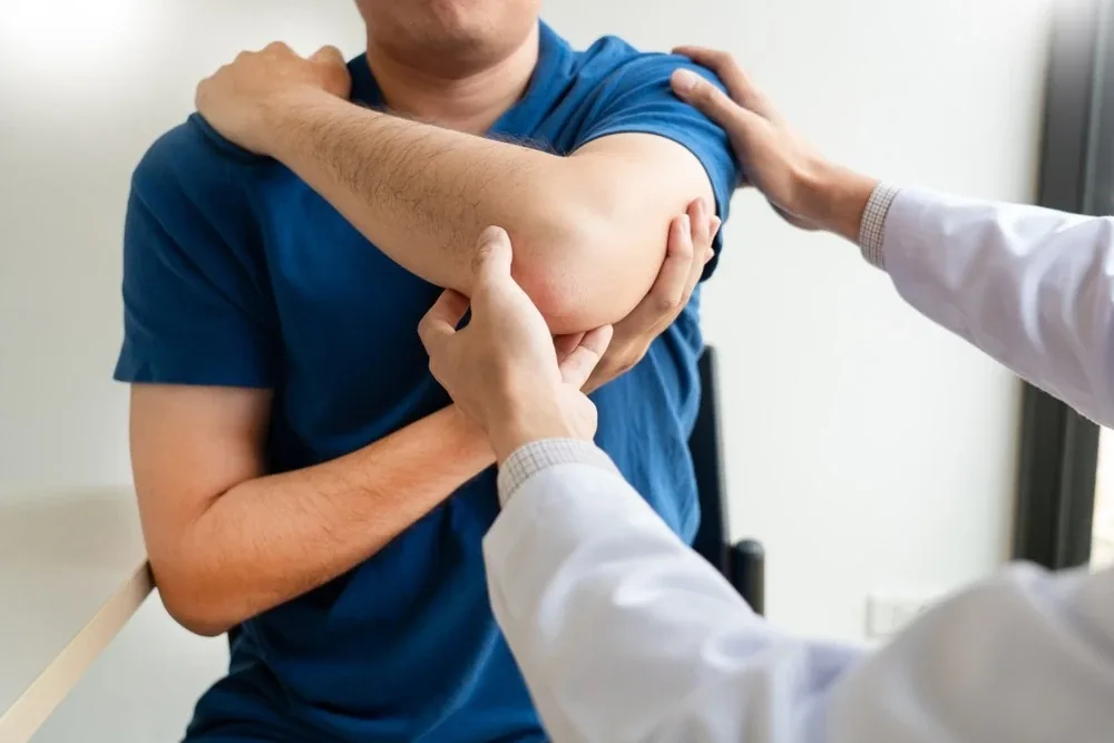 Physiotherapist mobilising a man's shoulder