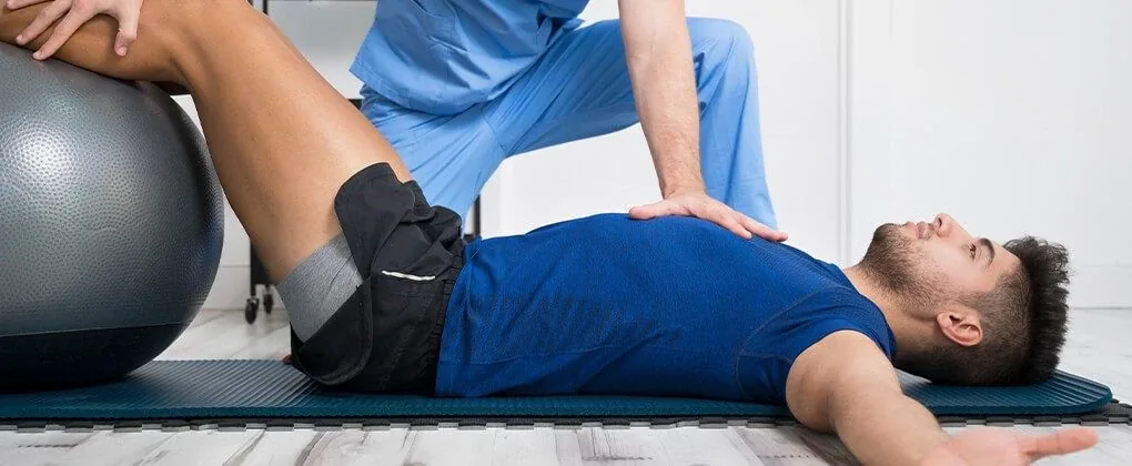 Physiotherapist treating a man during a floor exercise