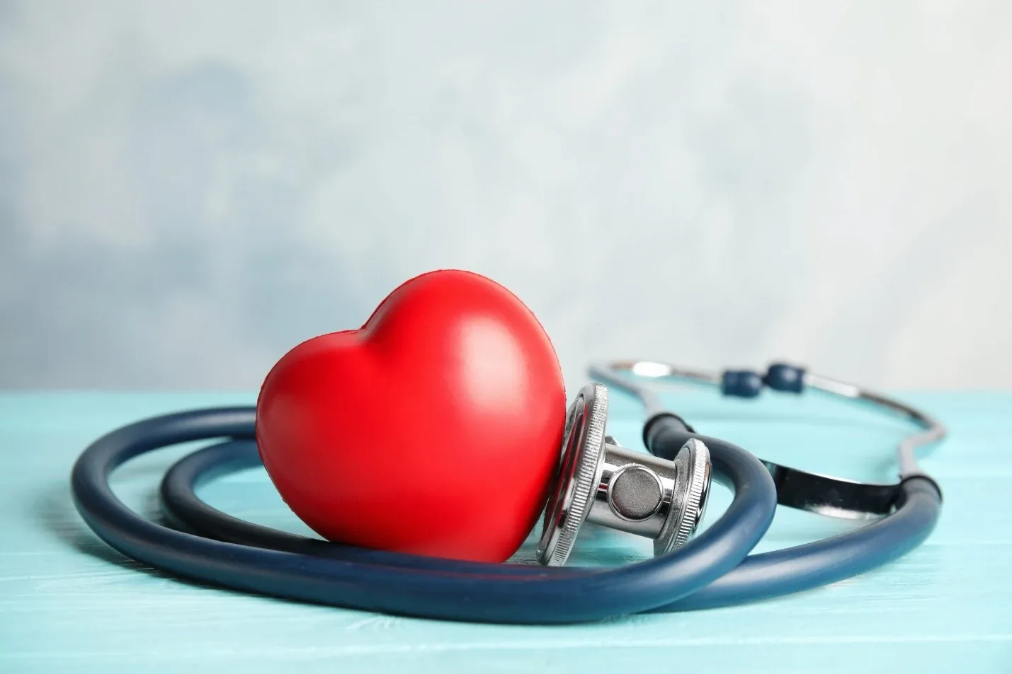 Red heart model beside a stethoscope