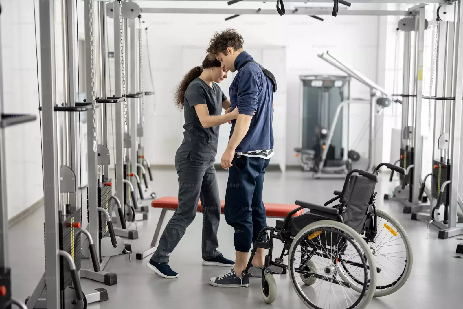 Physiotherapist assisting a patient to stand beside a wheelchair