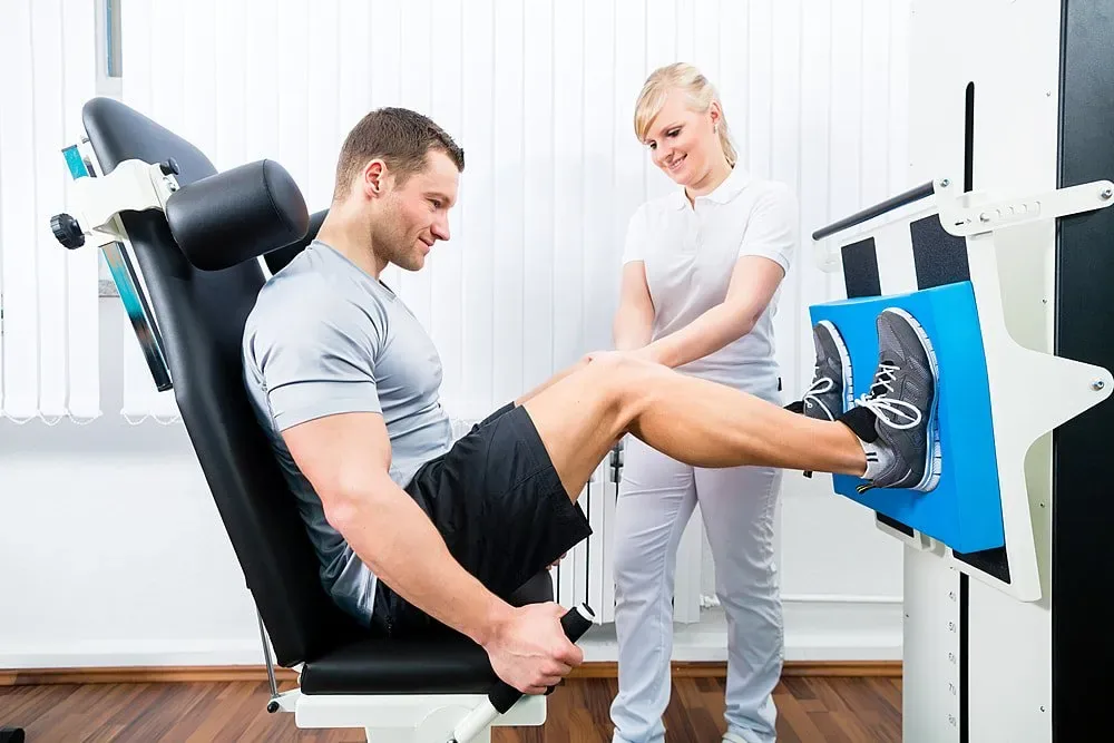 Sports rehabilitation therapists guiding an athlete on a leg press machine
