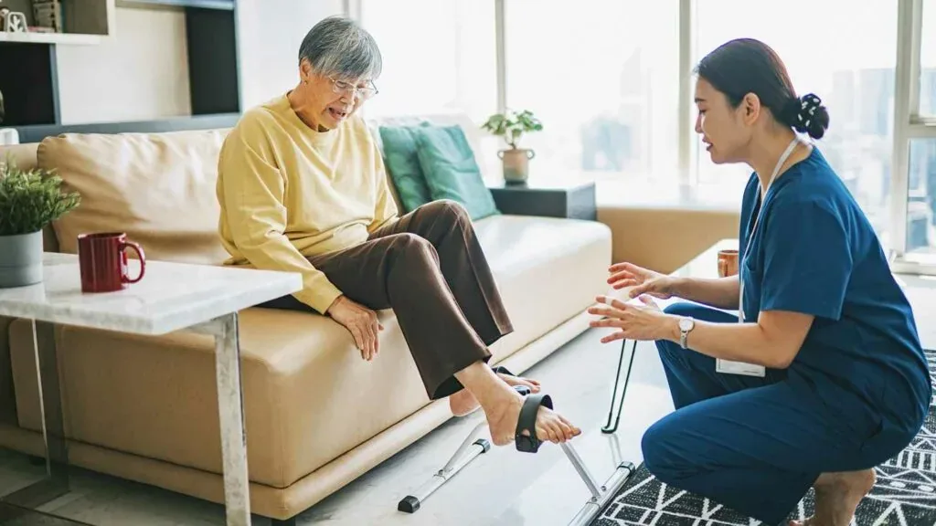Nurse helping a patient practise walking during stroke recovery at home