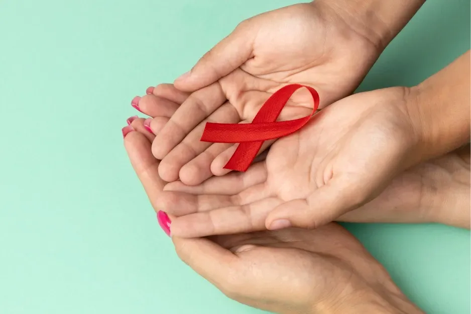 Hands holding a red HIV awareness ribbon