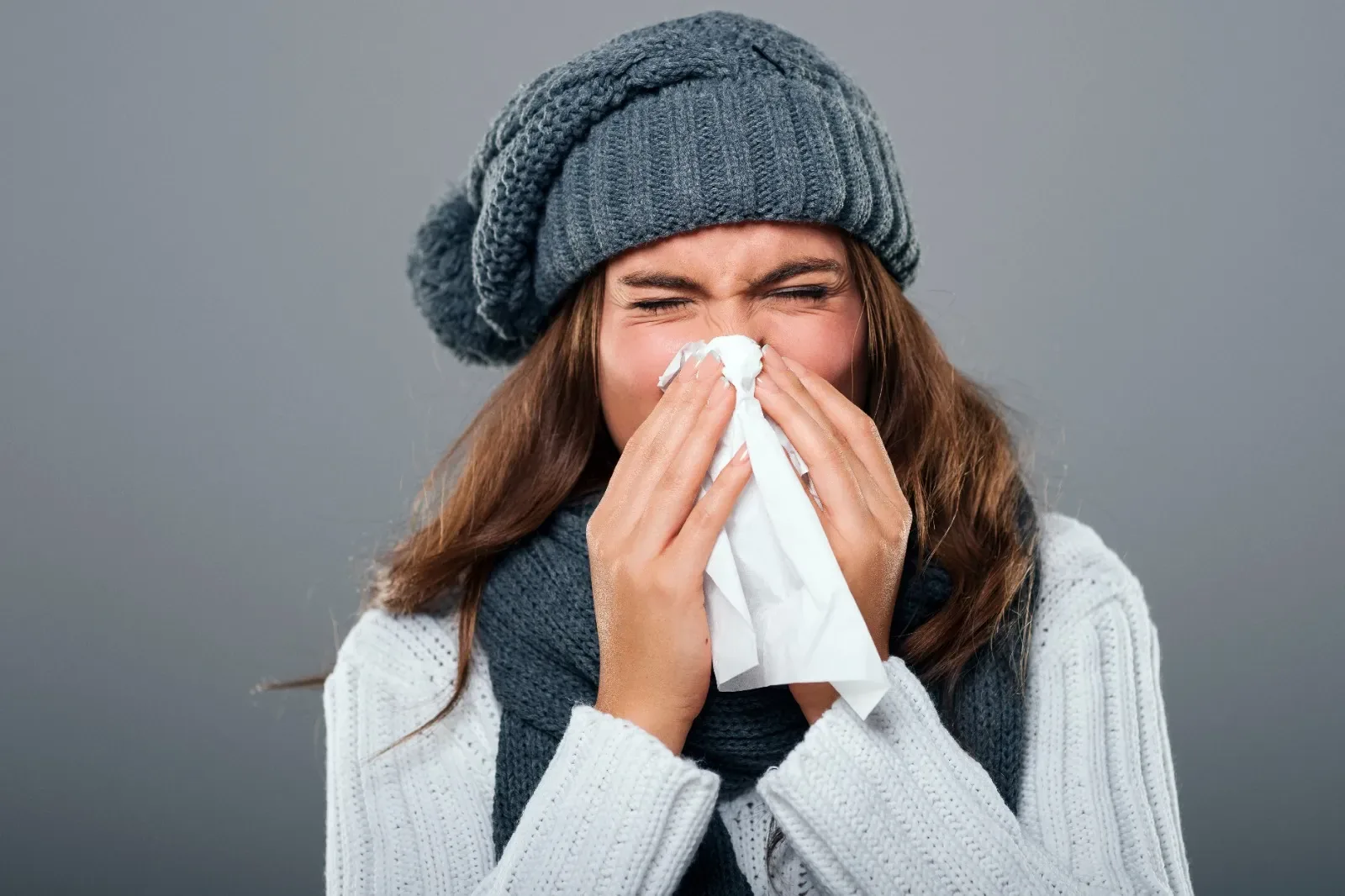 Woman in winter clothing blowing her nose