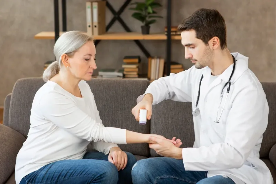 Doctor examining an older woman's arm during a home visit